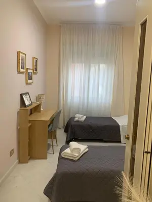 a bedroom with two beds and a desk and a window at Tiziano apartment-a spacious home for you in Rome in Rome
