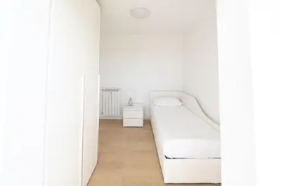 a white bedroom with a bed and a wooden floor at Caffarella Park Terraced 2BR Apartment in Rome