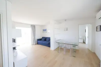 a white living room with a blue couch and a table at Caffarella Park Terraced 2BR Apartment in Rome