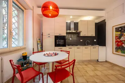 a kitchen with a white table and red chairs at ColoRHome in Rome