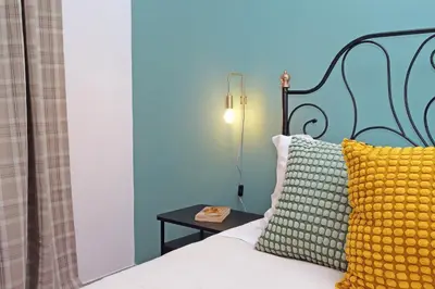 a bed with a blue headboard and a yellow pillow at TM Apartment in Rome