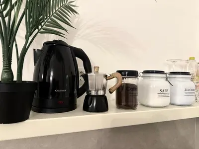 a black coffee pot and jars on a shelf at Biffi 2 - Garbatella Rooms in Rome