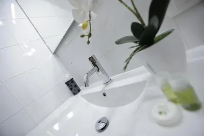 a white bathroom with a sink and a vase with flowers at The Holy Apartments in Rome