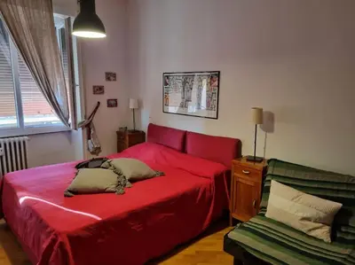 a bedroom with a red bed and a green couch at Casa BiBi in Rome