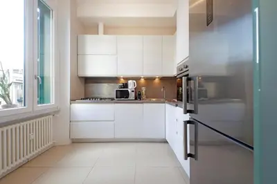 a kitchen with white cabinets and a stainless steel refrigerator at 4BNB - Armot House Vatican Apartment in Rome