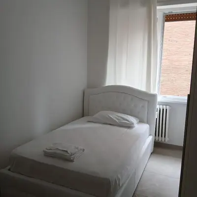a white bed in a white room with a window at Grand Nomentana Roma in Rome