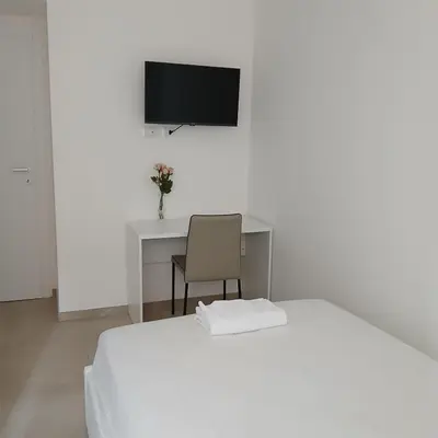 a bedroom with a bed and a desk with a television at Grand Nomentana Roma in Rome