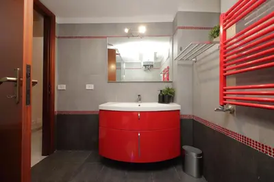a bathroom with a red sink and a mirror at Vatican Museums Art Apartment in Rome