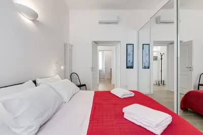 a white bedroom with a red blanket on a bed at Casa di Zio Colosseo in Rome