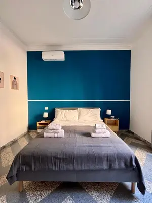 a bedroom with a large bed with a blue wall at The Place Strozzi in Rome