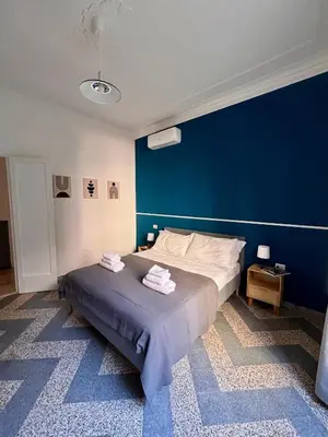 a bedroom with a large bed with a blue wall at The Place Strozzi in Rome