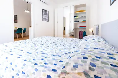 a white bedroom with a large bed with a colorful comforter at L'Appartamentino a San Giovanni in Rome