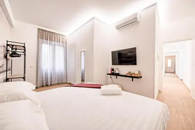 a white bedroom with two beds and a flat screen tv at Caesar's quarters - private rooms in Rome in Rome