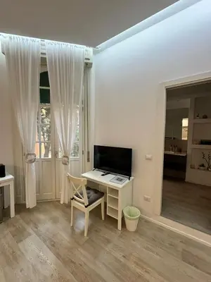 a white room with a desk and a television at Malila's-Cipitelli Trevi in Rome