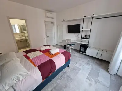 a bedroom with a bed and a desk and a television at Relux Pretoria Rooms in Rome