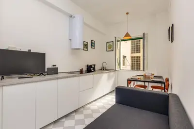 a kitchen with white cabinets and a tv and a table at NiMa Holiday 49 in Rome