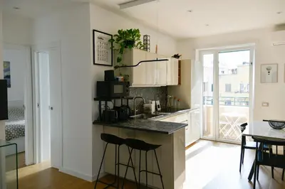 a kitchen with white cabinets and a counter with stools at Dima Home Cute Flat in Rome in Rome
