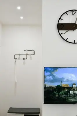 a clock and a tv on a white wall at Dima Home Cute Flat in Rome in Rome
