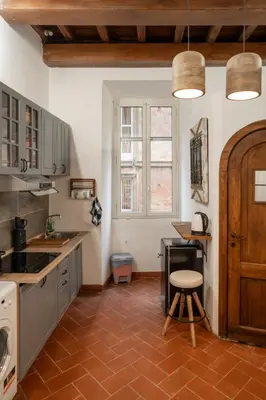 a kitchen with a counter and a table and a chair at Home Domus Capocci - Rione Monti in Rome