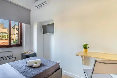 a small bedroom with a bed and a desk at La casa di Elba in Rome