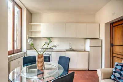 a kitchen with a glass table and blue chairs at Coliseum charming house in Rome
