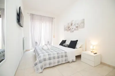 a white bedroom with a bed and a tv at Casa Luna in Rome