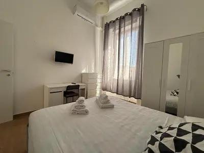 a white bedroom with a bed and a desk at Vaticano Apartment in Rome