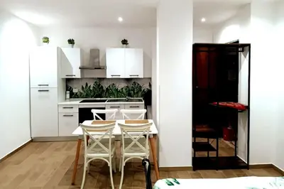 a kitchen with white cabinets and a table and chairs at Sweet Rome Holiday Flaminio-The biggest shower in Rome