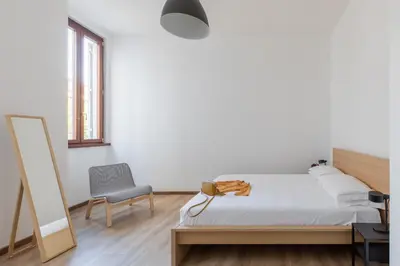 a bedroom with a bed and a chair and a mirror at iFlat Bright Brand New 3-Bedroom Apt in Monti in Rome