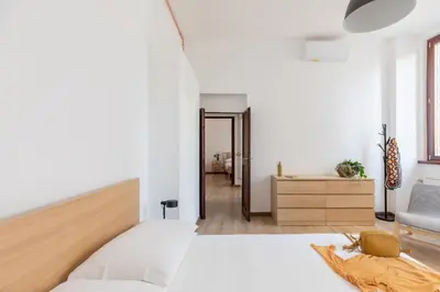 a white bedroom with a bed and a chair at iFlat Bright Brand New 3-Bedroom Apt in Monti in Rome