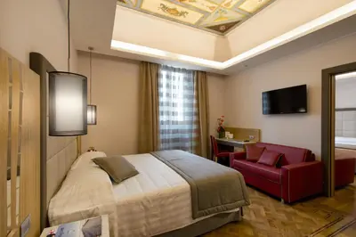 a hotel room with a bed and a red chair at Vibe Nazionale in Rome