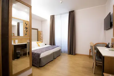 a hotel room with a bed and a table and a mirror at Vibe Nazionale in Rome