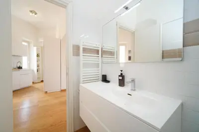 a white bathroom with a sink and a mirror at Clivo 2 St Peter BuddyRent in Rome