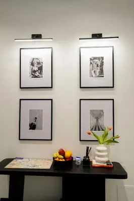 a table with pictures on a white wall with a shelf at No Man's Land Guesthouse in Rome