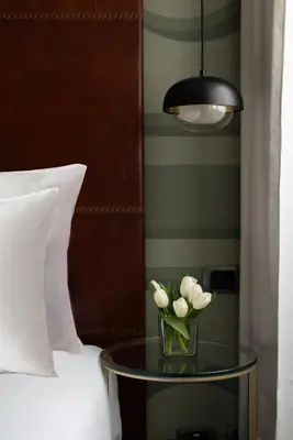 a vase of flowers on a table next to a bed at Maison Roma Piazza di Spagna UNA Esperienze in Rome