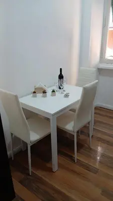 a white table with white chairs and a bottle of wine at Gianicolo House in Rome