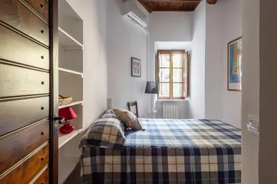 a bedroom with a bed with a plaid blanket at Trastevere Lungaretta apartment in Rome