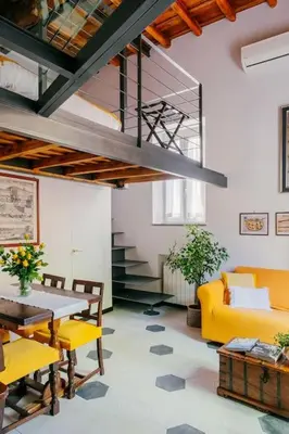 a living room with a yellow couch and a table at Charming restored loft in the heart of Trastevere in Rome