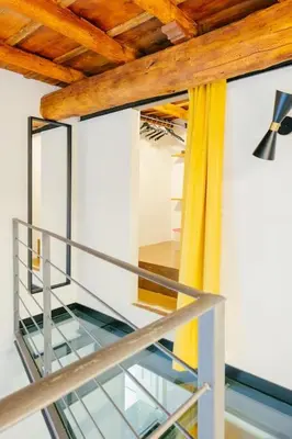 a glass staircase in a house with a yellow curtain at Charming restored loft in the heart of Trastevere in Rome