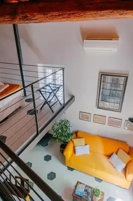 a living room with a yellow couch and a staircase at Charming restored loft in the heart of Trastevere in Rome