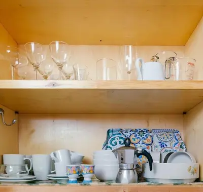 a shelf filled with cups and dishes and wine glasses at Charming restored loft in the heart of Trastevere in Rome