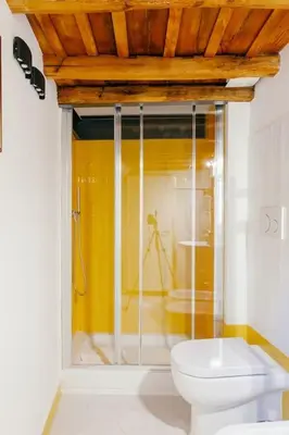 a bathroom with a toilet and a yellow wall at Charming restored loft in the heart of Trastevere in Rome