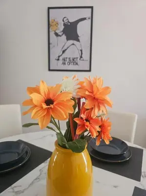 a yellow vase with orange flowers on a table at R home of art in Rome