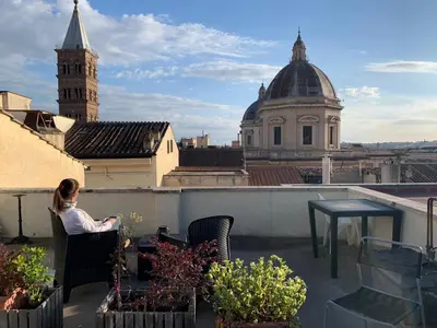 a woman sitting in a chair on top of a roof at G&A Rome House in Rome