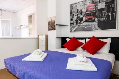 a bedroom with a blue bed with red pillows and a red bus at Montagnola Mini House in Rome