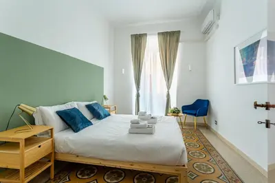 a bedroom with a bed and a blue chair at iFlat Colosseum's Brand New & Cozy Nest in Rome