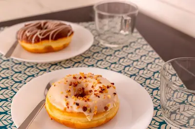 two donuts on white plates on a table at iFlat Colosseum's Brand New & Cozy Nest in Rome
