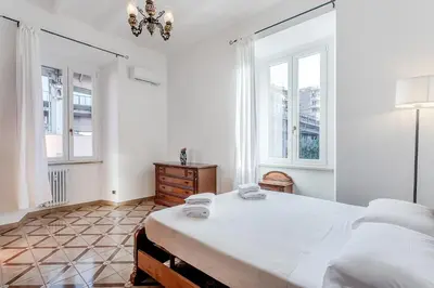 a white bedroom with a large bed and two windows at La Casa Viola in Rome