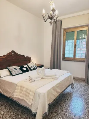 a bedroom with a large bed with a chandelier at Betty House Roma in Rome