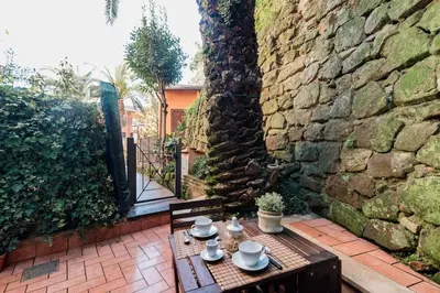 a table and chairs on a patio with a stone wall at Trastevere Cottage in Rome
